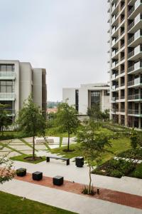 a park in front of a building with trees and benches at The Capital Trilogy Menlyn Maine in Pretoria