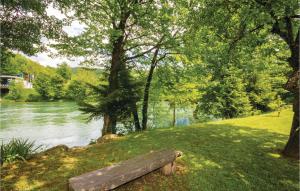 un banc en bois assis sur l'herbe à côté d'une rivière dans l'établissement 3 Bedroom Lovely Home In Blazevci, à Blaževci