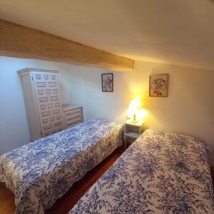 a bedroom with two beds and a lamp on a table at L'OCCITANE appartement climatisé centre ville in Limoux