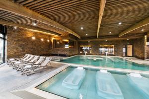 a large swimming pool with chairs in a building at Thalasso Concarneau Spa Marin Resort in Concarneau