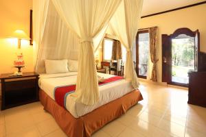 a bedroom with a bed with a canopy at Laghawa Beach Hotel in Sanur +24 photos