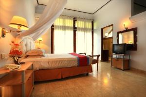 a bedroom with a bed with a table and a television at Laghawa Beach Hotel in Sanur