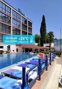 a pool with blue tables and chairs next to a building at Sochi-Breeze Spa Hotel in Sochi