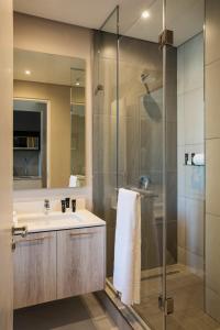 a bathroom with a sink and a glass shower at The Capital Trilogy Menlyn Maine in Pretoria