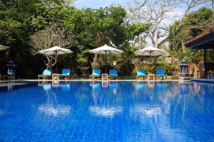a swimming pool with blue chairs and umbrellas at Laghawa Beach Hotel in Sanur