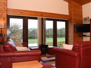 a living room with leather furniture and large windows at Sycamore Lodge in Rhayader