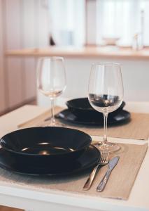 a table with two glasses of wine and a plate and knife at Ring Stop Holiday Apartment in Sigulda