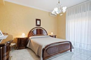 a bedroom with a large bed and a chandelier at Appartamento Sicilia Etna e Mare in Mascali