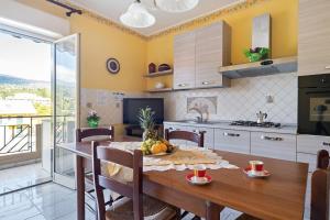 Il comprend une cuisine et une salle à manger avec une table et des chaises en bois. dans l'établissement Appartamento Sicilia Etna e Mare, à Mascali