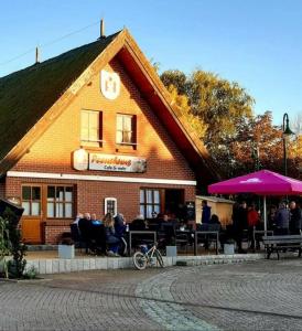 a building with people sitting outside of it at Urlaub am Peenestrom in Neukalen