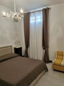a bedroom with a bed and a chandelier and a chair at Giardino sul Mare in Realmonte