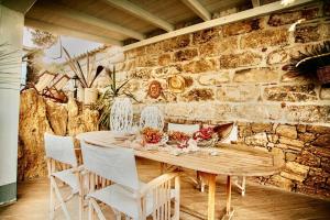 une table en bois avec des chaises blanches et un mur en pierre dans l'établissement Villa Dorotea con piscina, à Trappeto