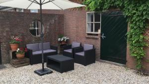 un patio con sillas y una sombrilla junto a un edificio en Boerengastenverblijf De Kromme Rijn, en Cothen