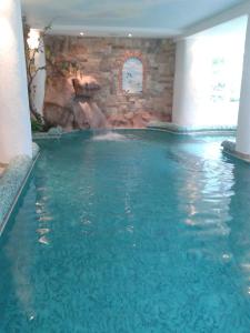 a swimming pool with a water slide in a building at Hotel des Alpes in Molveno
