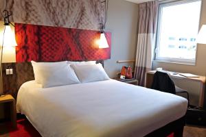 a hotel room with a large bed and a large window at ibis Moulins in Moulins