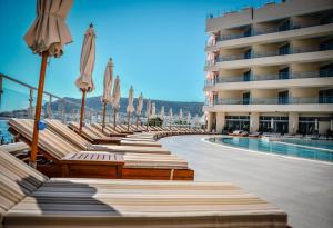 a row of chairs with umbrellas next to a swimming pool at Konstantinos Palace in Karpathos