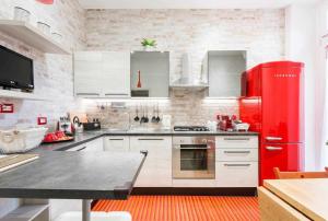 a kitchen with a red refrigerator and white cabinets at Little House in the centre Nettuno in Nettuno