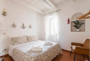a white bedroom with a bed and a chair at Little Medieval House Nettuno in Nettuno