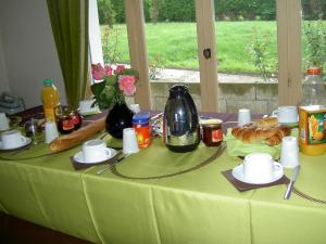 einen Tisch mit einem grünen Tischtuch mit Essen drauf in der Unterkunft Le Bon Accueil in Val Couesnon
