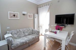 een woonkamer met een bank, een tafel en een tv bij Charming and Cozy House in Nettuno
