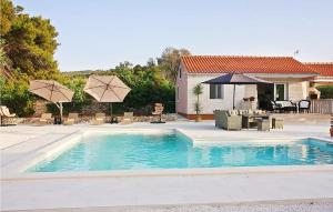 een zwembad met stoelen en parasols naast een huis bij Nice Home In Supetar With Private Swimming Pool, Can Be Inside Or Outside in Supetar