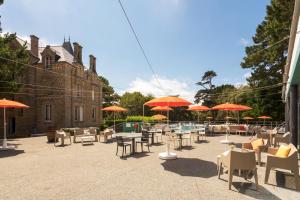 a patio with tables and chairs and umbrellas at Hotel Ker Juliette in Pornichet