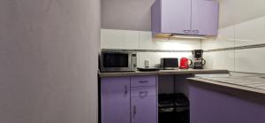 a kitchen with purple cabinets and a microwave at Zimmer am Schwielowsee in Schwielowsee