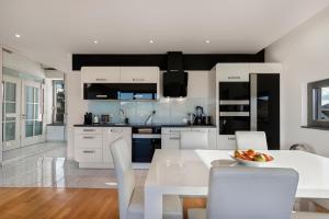 a kitchen with white cabinets and a white table and chairs at Contemporary apartment with rooftop terrace in Maribor in Maribor