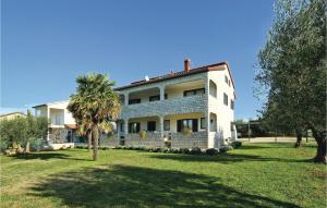 a large white house with a palm tree in front of it at Beautiful Apartment In Porec With 3 Bedrooms And Wifi in Poreč