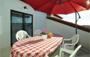 a table with chairs and a red umbrella on a balcony at 3 Bedroom Gorgeous Apartment In Porec in Poreč