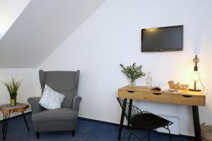 a chair and a desk with a television on a wall at Hotel Baroko in Prague