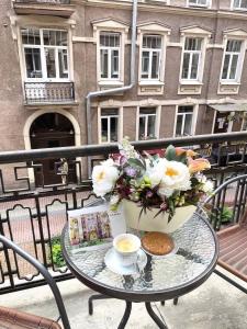 una mesa con una taza de café y flores en el balcón en Anabel at Nevsky 88, en San Petersburgo