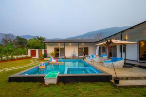a swimming pool with chairs and a house at SaffronStays Turquoise Maison - 3BR pool villa with jacuzzi, bonfire & fruit garden near Lake Kalote, Karjat in Karjat