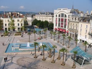 a city square with a fountain and palm trees at Hotel Le Bourbon Pau Centre in Pau