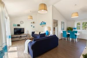sala de estar con sofá azul y TV en Sardinia Hostay Holiday House With Garden Sant'Isidoro, en Sant' Isidoro