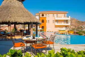 una piscina con mesas y sillas junto a un edificio en The Ridge at Playa Grande, en Cabo San Lucas