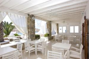 a restaurant with white tables and chairs and windows at Anixi Hotel in Ornos