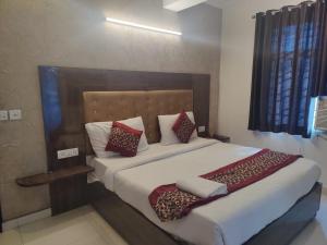 1 dormitorio con 1 cama grande con almohadas rojas y blancas en Hotel Ark Avalon- Delhi International Airport en Nueva Delhi