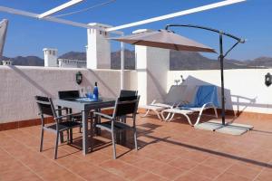 - une table, des chaises et un parasol sur la terrasse dans l'établissement Nuestra Casa apartamento con terraza azotea y piscina compartida, à San Juan de los Terreros