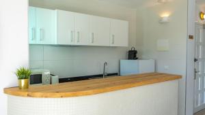 a kitchen with white cabinets and a wooden counter top at Tabbu ibiza apartments in Playa d'en Bossa