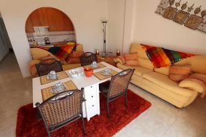 een woonkamer met een tafel en een bank bij El Cid apartamento soleado vista panorámica al mar y piscina comunitaria in San Juan de los Terreros