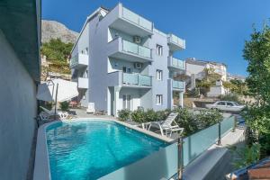 an apartment with a swimming pool in front of a building at Apartments Lorenzo in Lokva Rogoznica