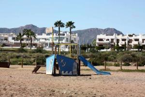 - une aire de jeux sur la plage avec des bâtiments en arrière-plan dans l'établissement Girasol apartamento para 4 personas con piscina communitaria, à San Juan de los Terreros