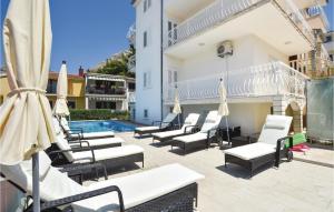 a group of chairs and umbrellas next to a pool at Stunning Home In Podstrana With Wifi in Strožanac