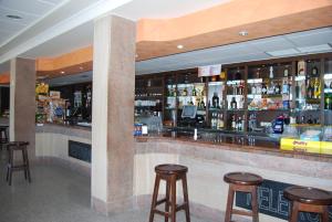 a bar with wooden stools and bottles of alcohol at Hotel Meleiros in Castro de Sanabria