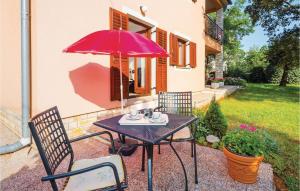 a table with a red umbrella and two chairs at Apartment Labin Presika Ii in Labin