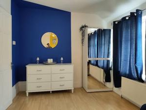 a bedroom with blue walls and a dresser and a mirror at Cheerful Gem of Barking & Dagenham 3 Bedroom House Entire Property in Goodmayes