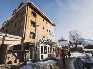 a person walking in front of a building in the snow at Hotel Base Camp Lodge - Les 2 Alpes in Les Deux Alpes