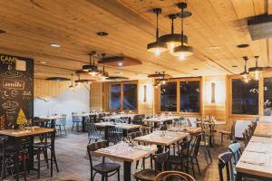 a restaurant with wooden ceilings and tables and chairs at Hotel Base Camp Lodge - Les 2 Alpes in Les Deux Alpes