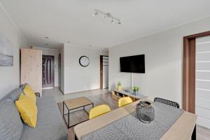 a living room with a table and yellow chairs at Comfort Apartments Gdynia Centrum in Gdynia